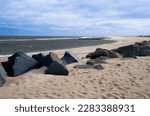 Sandy beach with boulders on the Atlantic Ocean. Blue sky with wispy clouds on a winter