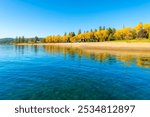 The sandy beach City Beach and autumn colored trees along City Park near Independence point on lake Coeur d