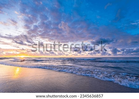 Sandy beach, colorful sky slightly cloudy at sunset, sea waves