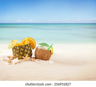 Sandy beach with fresh drinks in pineapple fruit
