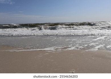 Sandy Beach with Gentle Waves and Clear Sky. Serene coastal view featuring a sandy beach with gentle ocean waves and a clear blue sky, perfect for tranquil seascape and nature themes. - Powered by Shutterstock