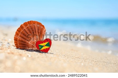 Sandy beach in Grenada. Flag of the Grenada in the shape of a heart and a large shell.
