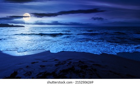 sandy beach at night. beautiful seascape background. calm waves washing the shore. clouds glowing in full moon light. summer vacation and relaxing recreation concept - Powered by Shutterstock