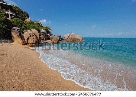 Sandy beach with several large rocks protruding from the water, creating a striking contrast between the shoreline and the ocean