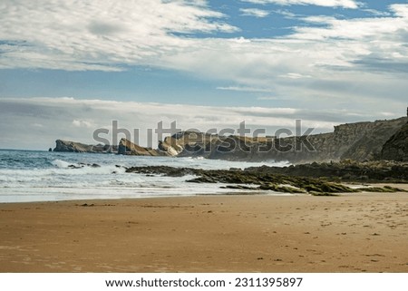 Sandy beach and steep cliffs in Dunes of Liencres Natural Park, Cantabria, Spain