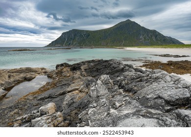 Sandy beach with stones and clear water pond and rocky mountains in cloudy background, Lofoten Norway - Powered by Shutterstock