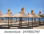 Sandy beach with straw umbrellas and beach loungers on the Olympic Riviera, Nei Pori, Pieria - Greece
