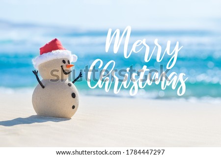 Sandy Christmas Snowman is celebrating Christmas on a beautiful beach with Merry Christmas wishes in the background