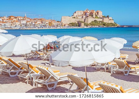 Sandy Corsican beach and amazing azure sea with an ancient citadel of Calvi in background. Historical touristic place.