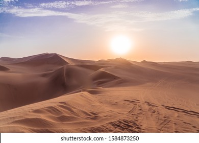 Sandy desert at sunset. Dry, hot sand deserted vibes. Travel, holiday, explore scenic shot, with sand ripples, sun setting and footprints. Tourism shot in Huacachina, Peru. Epic, dramatic shot.  - Powered by Shutterstock