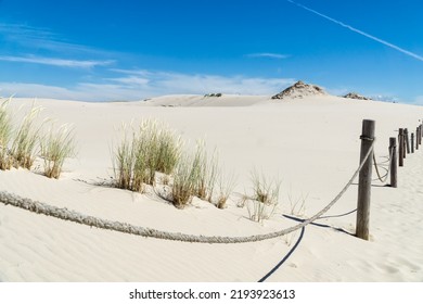 Sandy dunes overgrown by clumps of grass  and blue sky with white clouds in sunny summer day.  Lacka dune in Slowinski National Park in Poland, a miracle of nature. Traveling dune.  - Shutterstock ID 2193923613