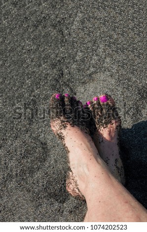 Sandy feet on a black sand beach.
