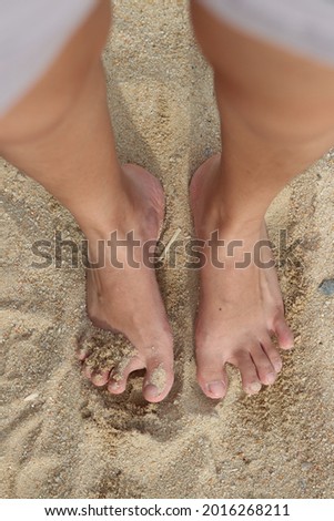 sandy feet from top view at the beach with silver frame at the side during daytime