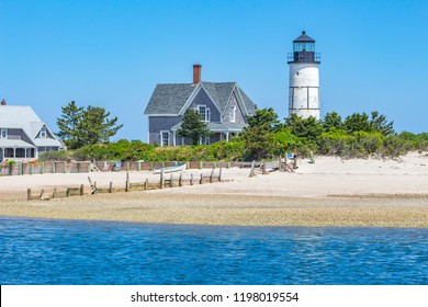 Sandy Neck Lighthouse Dotting The Blue Coast Of Cape Cod Bay Along A Sandy Beach. 