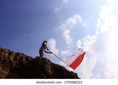 Sangatta, East kalimantan / Indonesia: 08 August 2020 - A man stands with an Indonesian flag, Standing on a hill holding a flag - Shutterstock ID 1792086521