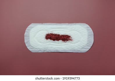 Sanitary pad with red glitter on pink background. Woman menstruation cycle and critical days.
