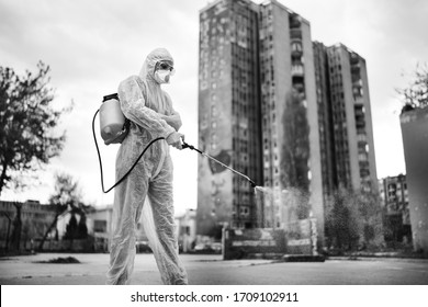 Sanitation service worker disinfecting public space with disinfectant spray.Street disinfection.Coronavirus COVID-19 pandemic outbreak prevention and protection.Hazmat protective suit / gear (PPE) - Powered by Shutterstock