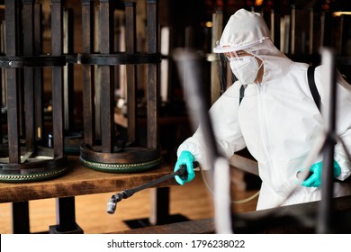 Sanitation worker in protective suit disinfecting empty cafe during COVID-19 epidemic.  - Powered by Shutterstock