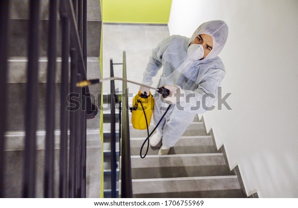 Sanitizing interior surfaces.\
Cleaning and Disinfection inside buildings, the coronavirus\
epidemic. Infection prevention and control of epidemic. Protective\
suit and mask.