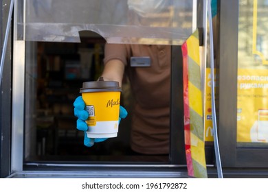 Sankt-Petersburg Russia - April 18 2021: McDonalds Worker Holding Cup Of Coffee To Go In Hand  Through The Window Of Mcdonalds Car Drive Thru Service.