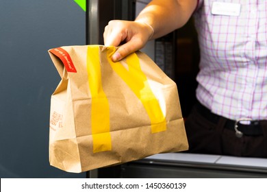 Sankt-Petersburg/Russia - July 11 2019: McDonald’s Worker Holding Bag Of Fast Food. Hand Through The Window Of Mcdonalds Car Mcauto.