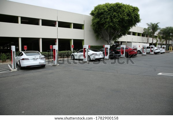 Santa Ana, California / USA - July 23, 2020:\
Tesla Electric Car Charging Station in a Shopping Mall Parking Lot.\
Tesla brand Electric Cars are being charged with electricity at a\
Charging Station.
