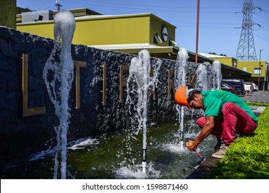 Santa Ana, San José/Costa Rica-11/22/19: hardworking latino maintenence handyman fixing water fountain plumbing on sunny day