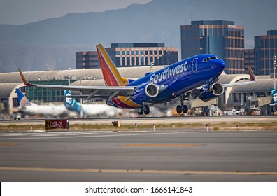 Santa Ana,Ca/USA-02/03/20:Southwest Airlines passenger jet taking off at John Wayne Airport with aircraft and buildings in Irvine,Ca in distance