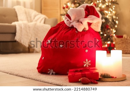 Santa bag, Christmas gift and burning candles in living room, closeup
