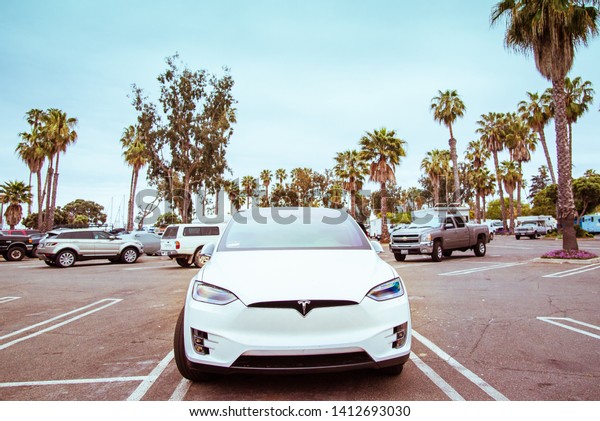 Santa Barbara, California, USA - May 31, 2018:
Electric luxury Tesla car on beach parking lot reserved for ecology
cars. Parking near Yacht Club, Santa Barbara beach, tropical palm
trees background