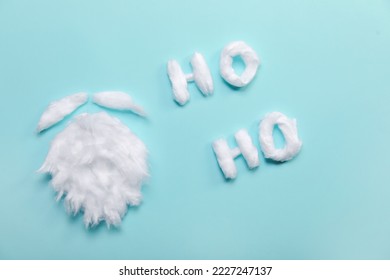 Santa beard made of cotton wool and words HO HO on blue background