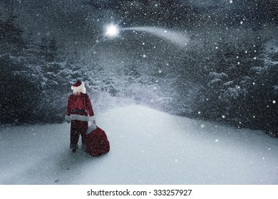 Santa Carrying Sack Of Gifts Against Snow Scene