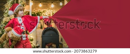 Santa child pulling huge bag of gifts, banner isolated on red background with copy space. Adorable child play with bag full of presents on christmas tree at home.