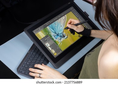 SANTA CLARA, Calif., Feb. 25, 2022: A female digital artist draws a digital picture on a Wacom Сintiq graphics tablet with a stylus (pen) using Adobe Photoshop software