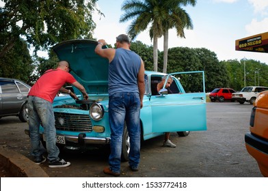 Santa Clara, Cuba - December 2016: Men Arranging A Broken Down Blue Classic Car On A Petrol Station Parking Lot.