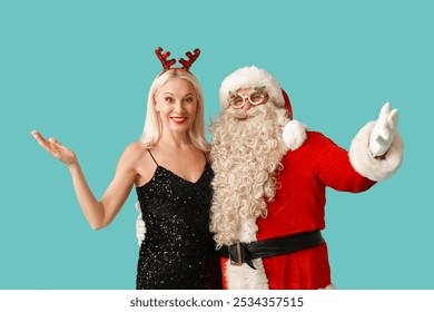 Santa Claus with beautiful mature woman in Christmas deer horns and glasses on blue background - Powered by Shutterstock