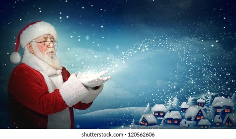 Santa Claus blowing snow to blue  little town at night - Powered by Shutterstock