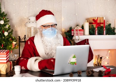 Santa Claus in blue medical protective mask types on laptop computer at workshop - Powered by Shutterstock