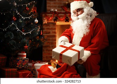 Santa Claus brought gifts for Christmas and having a rest by the fireplace. Home decoration.