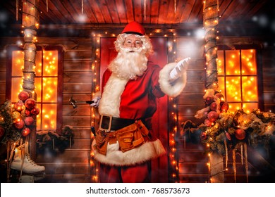 Santa Claus is a builder. House of Santa Claus. Portrait of Santa Claus with tools in his hands and a helmet on his head standing near his decorated house. Christmas and New Year concept.
