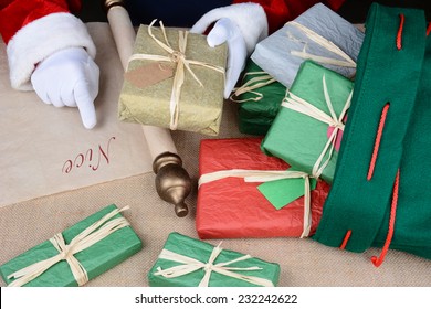 Santa Claus checking his list as he packs his bag for delivery on Christmas Eve. Horizontal format closeup showing only Santa's hands, presents and his bag. - Powered by Shutterstock