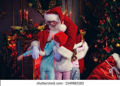 Santa Claus cuddles with little girls at home. Merry Christmas and Happy New Year. Miracle time.