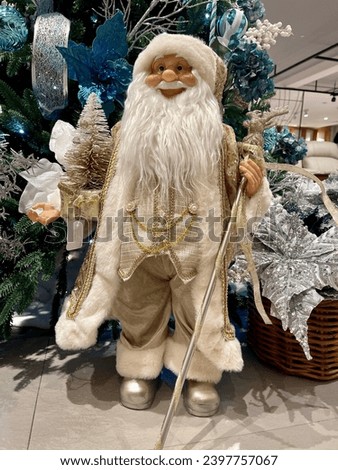 Santa Claus doll figure wearing a shiny gold robe holding a gold dragon staff as a complement to the Christmas tree decoration at home. Jakarta, Indonesia. 2023.