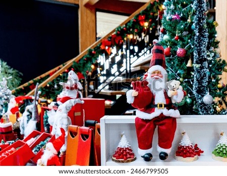Santa Claus doll holding red gift bag and white beer sitting on the white wooden shelve with copy space background. Christmas concept.