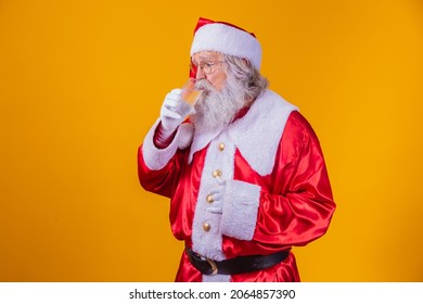 Santa Claus Drinking A Glass Of Water On Yellow Background With Space For Text. Health And Hydration Concept