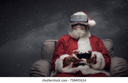 Santa Claus experiencing virtual reality at home and playing videogames using a controller, he is wearing a VR headset and he is surrounded by snow - Powered by Shutterstock