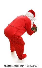 Santa Claus In Footy Pajamas, Bending Over To Pick Up A Present.  Full Body Isolated On White.