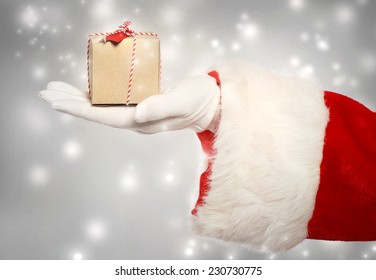 Santa claus giving a small christmas present box in snowy night  - Powered by Shutterstock