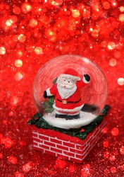 Santa Claus In Glass Ball On Red Abstract Shiny Background. Symbol Of New Year And Christmas Holidays. Festive Winter Season. Template For Design