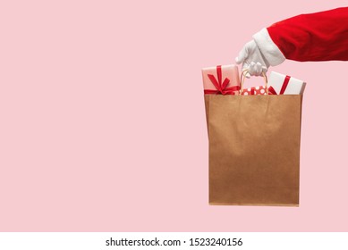 Santa Claus Hand Holding Brown Shopping Bag With Gift Boxes On Isolated Background. Black Friday, Sales, Giving Gift For Christmas And New Year 2019 Concepts.